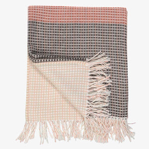 a lyric collection read and black wrap, blanket or throw sustainably and ethically made in South Africa shows the intricate weave and colors folded up on white background