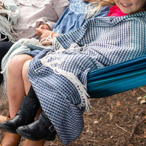 Kids lying on a hammock drapped in lyric collection blue and white wrap, blanket or throw sustainably and ethically made in South Africa