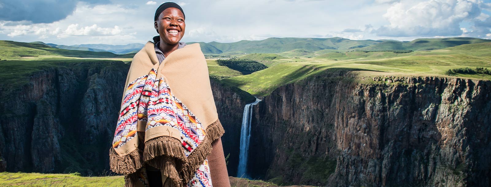 History Of the Basotho Heritage Blanket African Women standing infront of Lesotho waterfall wrapped in Basotho Blanket