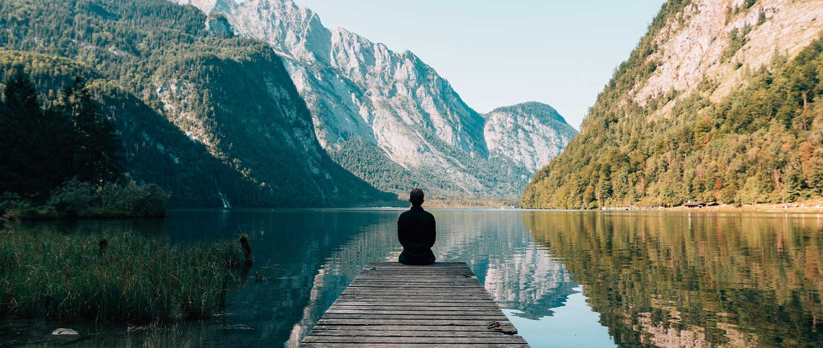 Meditating and mediation blankets go hand in hand man sitting in front of beautiful lake and mountain landscape 