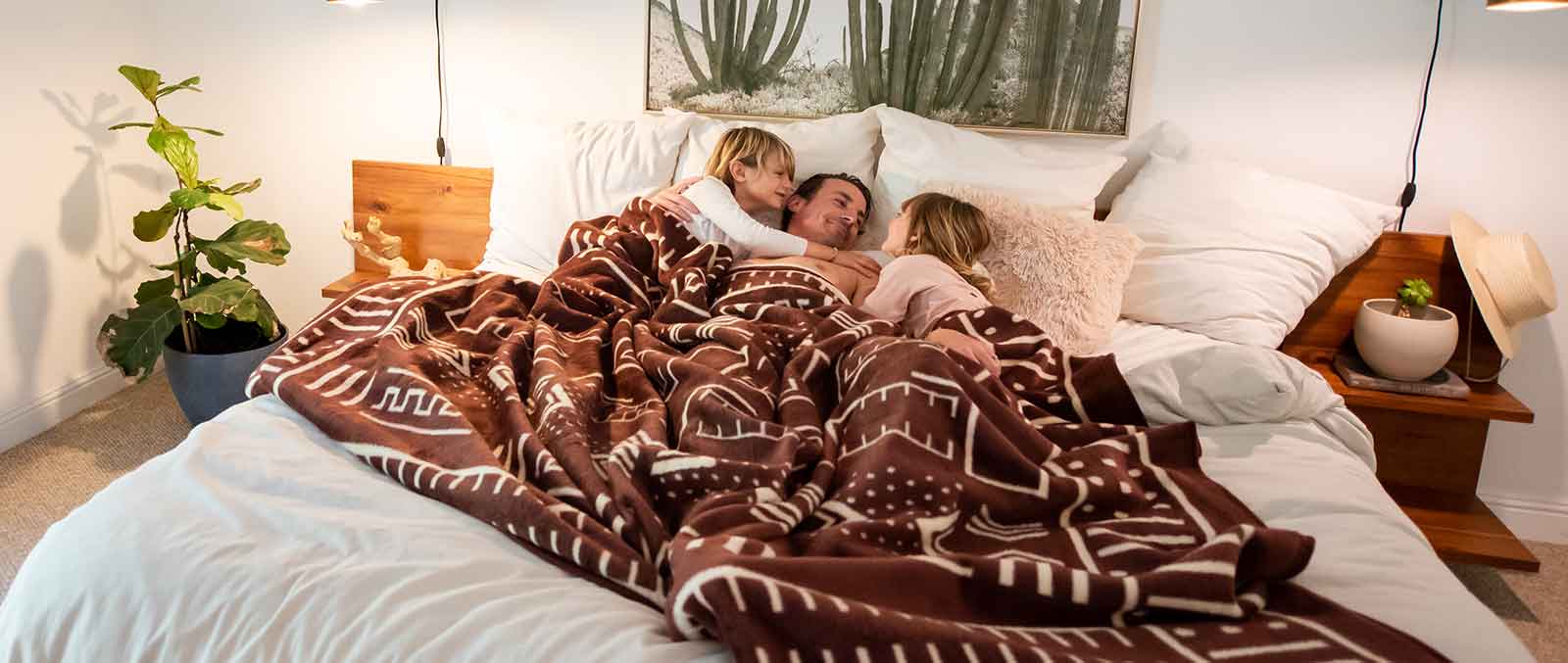 A women is sleeping on the bed with her kids in the blanket