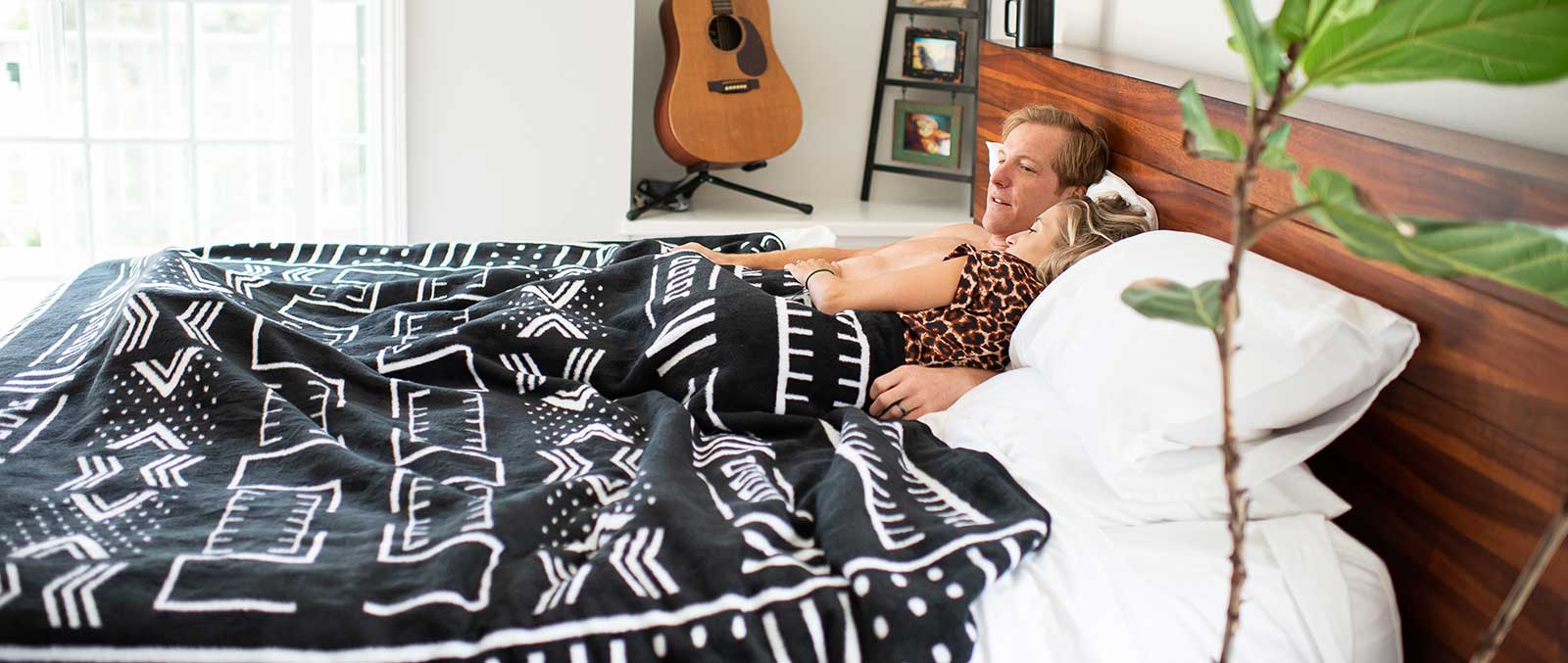 couple lying under a black and white african designed blanket 