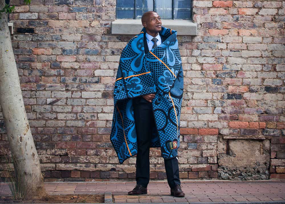 a gentleman is standing in front of wall and wrapped in blanket by thula tula
