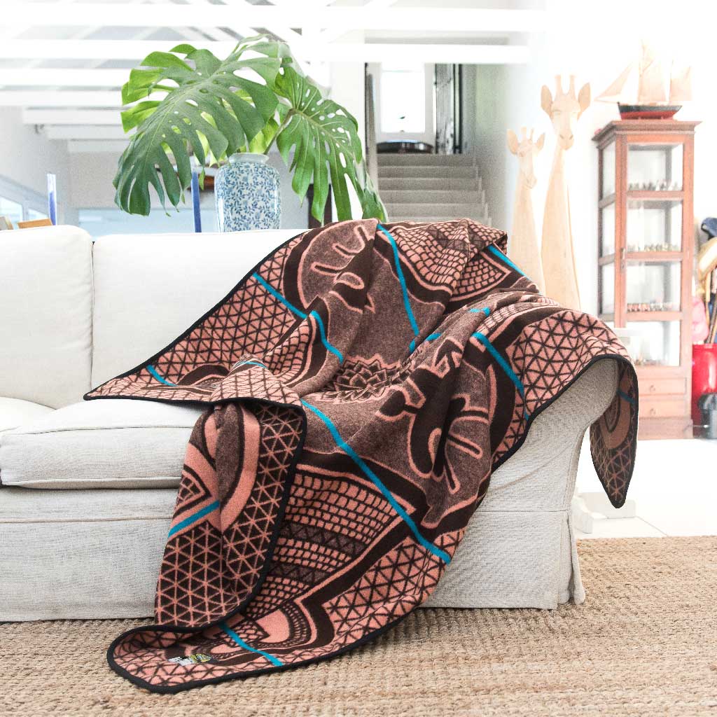 Basotho Heritage blanket and wrap or throw handcrafted in South Africa chromatic Salmon and peacock throw drapped across a sofa in a beautiful modern house