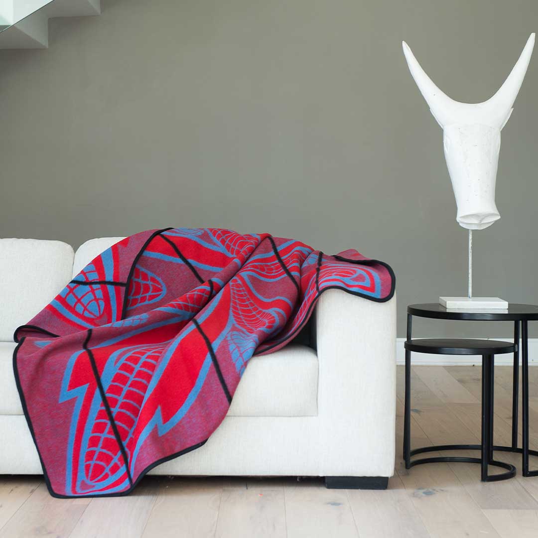 Heirloom Basotho Wool Blanket - Scarlet and Cobalt laying on sofa