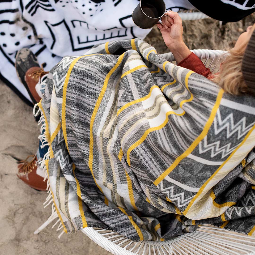 This Image is of a Kente throw used in an outdoor camping and campfire setting. This beautiful and vibrant throw Ghana Kente throw Sustainably and ethically crafted in South Africa, the My Africa collection is a range of incredibly soft, warm, and exceptionally durable blankets that take their inspiration from the cultures and people that inhabit this beautiful land. 