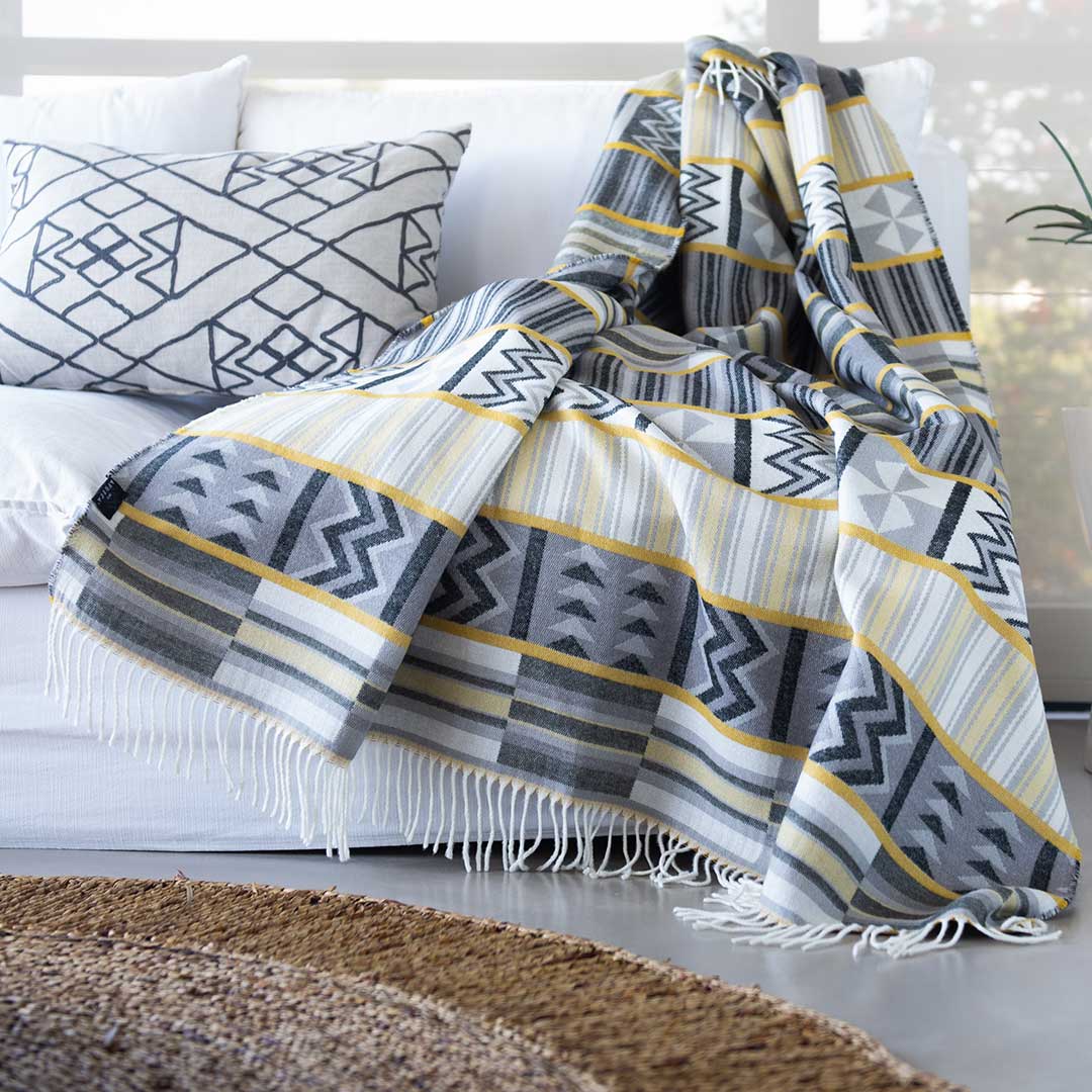 This beautiful and vibrant throw Ghana kente Throw Sustainably and ethically crafted in South Africa, the My Africa collection is a range of incredibly soft, warm, and exceptionally durable blankets that take their inspiration from the cultures and people that inhabit this beautiful land. This Image is of a Kente throw draped over a modern couch in an African House