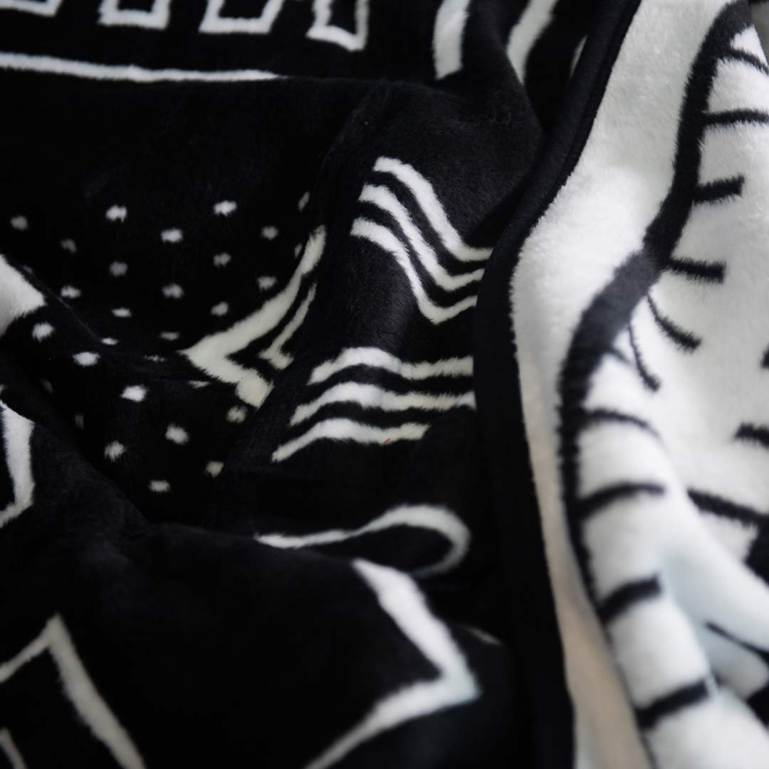 Extreme close up of black and white Mali cotton suede Mud Cloth wrap, blanket or throw sustainably and ethically made in South Africa drapped that shows the intricate weave and colors of the blanket