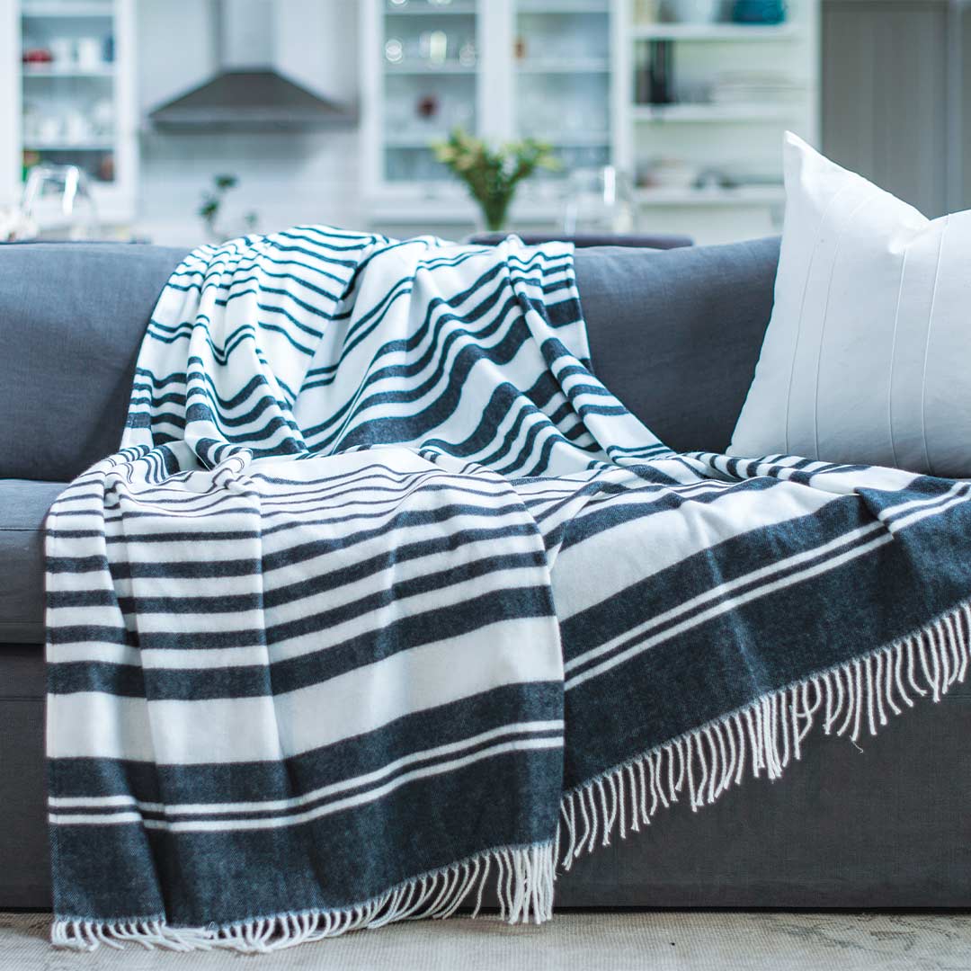Xhosa Nation wrap, blanket or throw sustainably and ethically made in South Africa. This xhosa inspired Black and white stripe is draped over a grey couch in a modern home