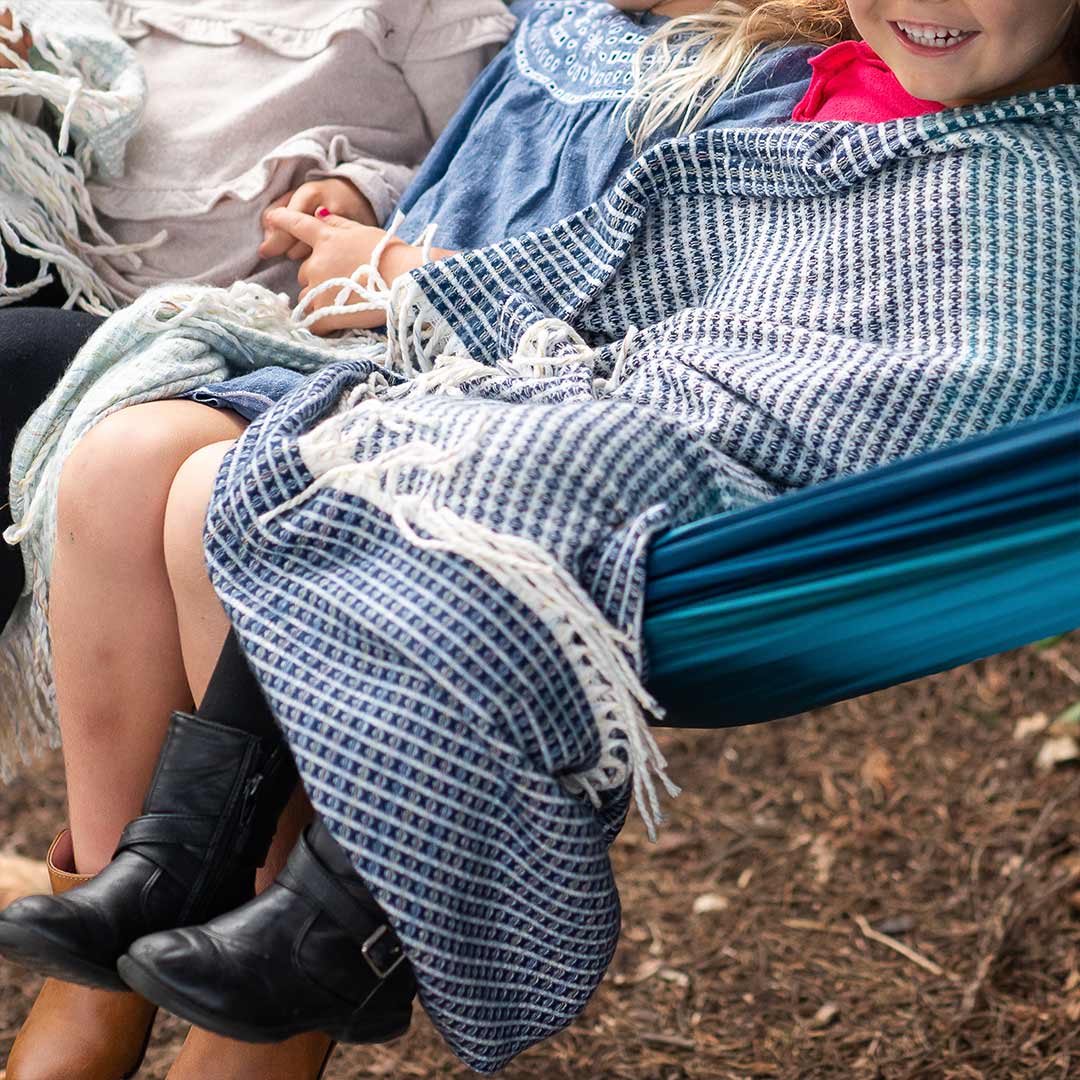 Kids lying on a hammock drapped in lyric  collection blue and white wrap, blanket or throw sustainably and ethically made in South Africa 