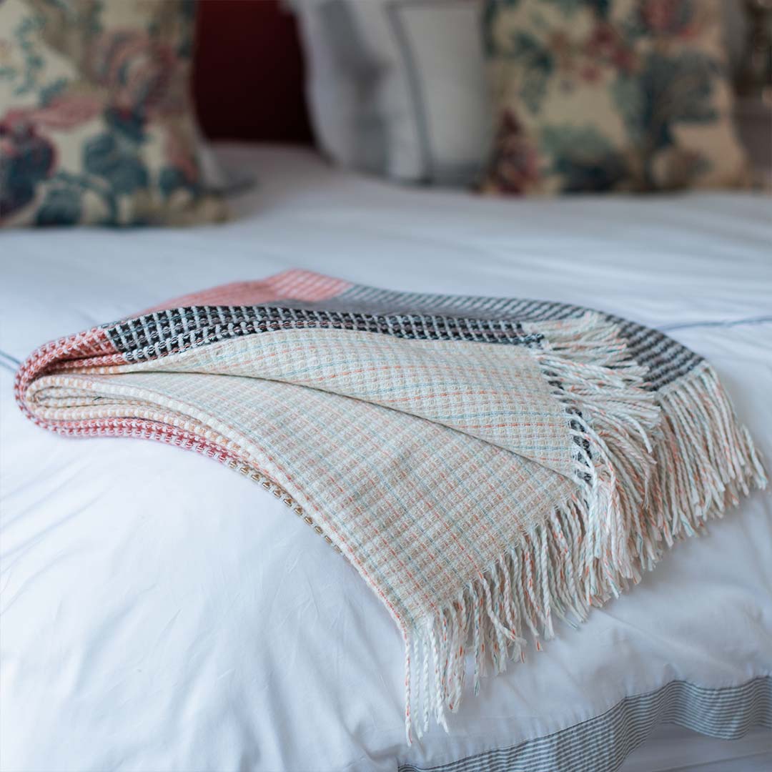  lyric collection read and black wrap, blanket or throw sustainably and ethically made in South Africa shows the intricate weave and colors folded up on a white bed