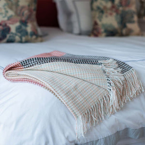  lyric collection read and black wrap, blanket or throw sustainably and ethically made in South Africa shows the intricate weave and colors folded up on a white bed