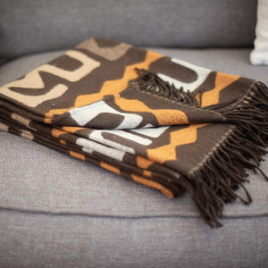 African inspired designed Congolese kuba cloth wrap or blanket Made in South Africa lying folded on a modern fabric chair
